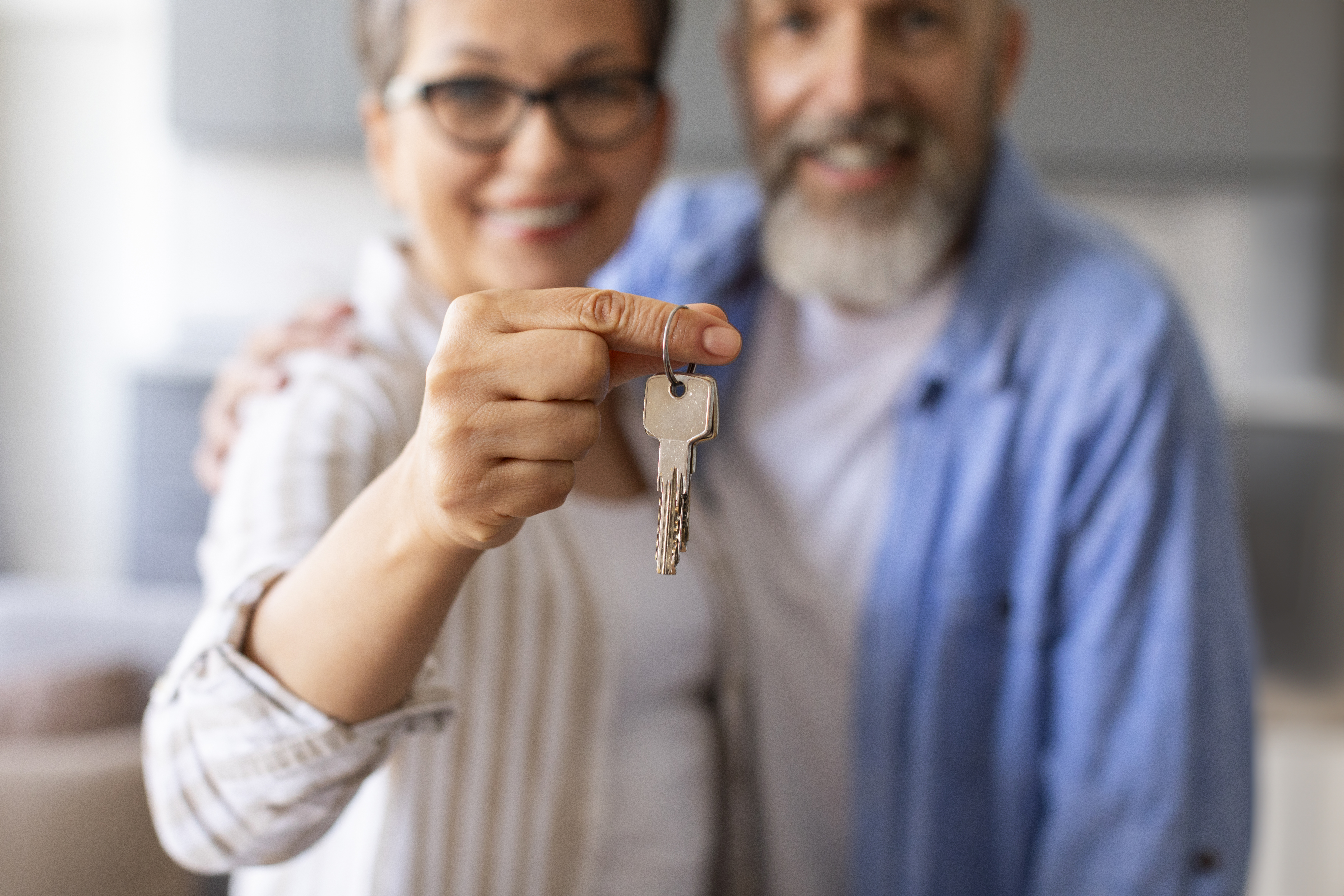 Real Estate Concept. Happy Senior Couple Holding Home Keys, Showing To Camera