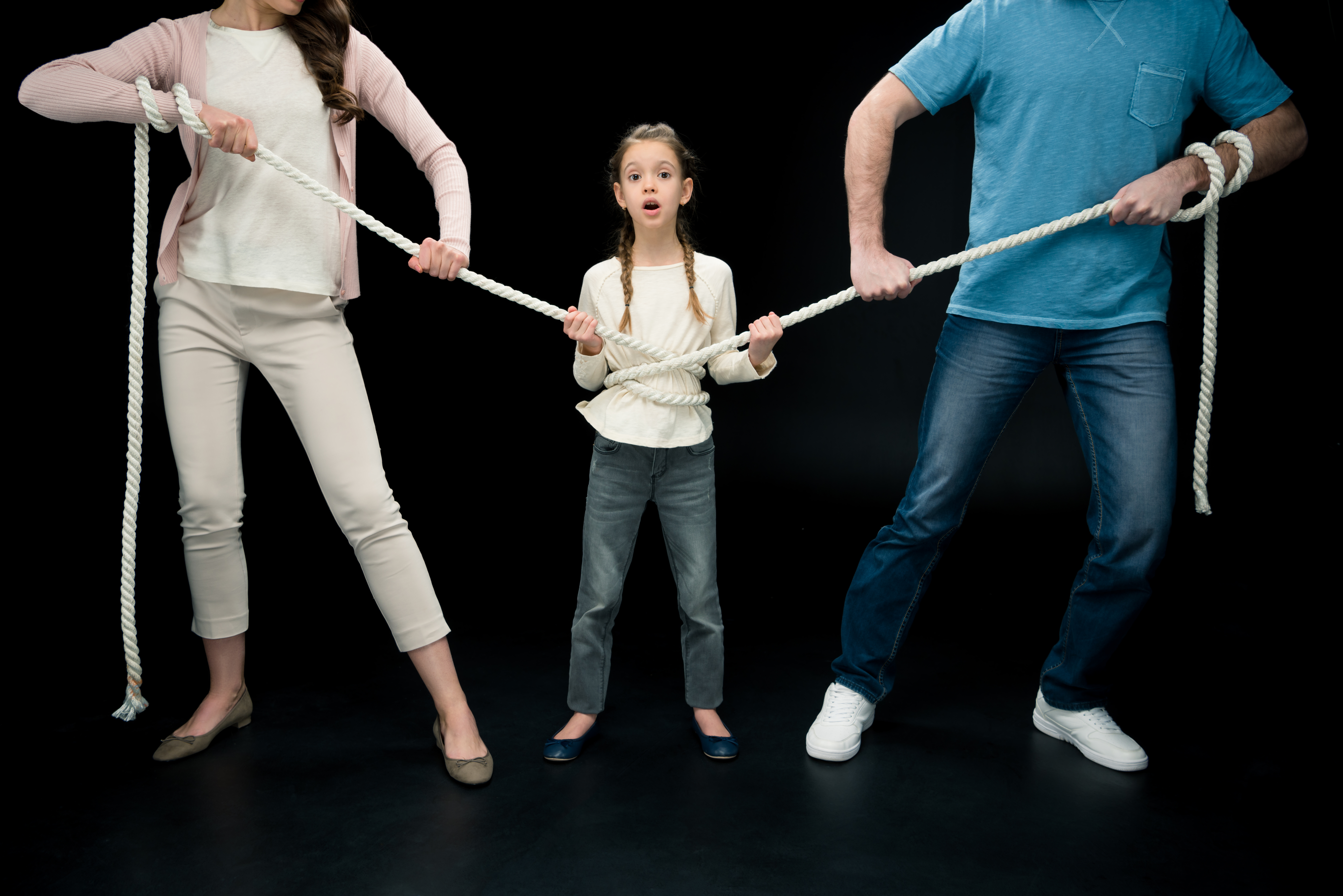 parents pulling over shocked daughter with rope isolated on black, divorce and separation concept